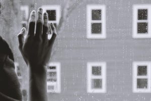 a hand placed on a window, raining outside