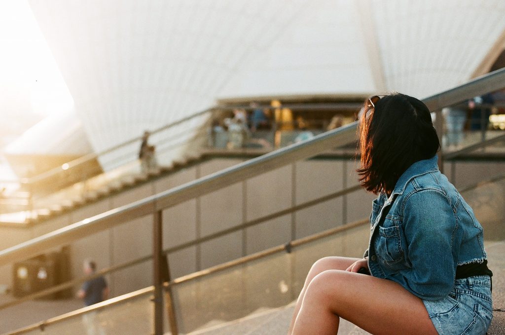 woman sitting on some steps looking towards a sunset