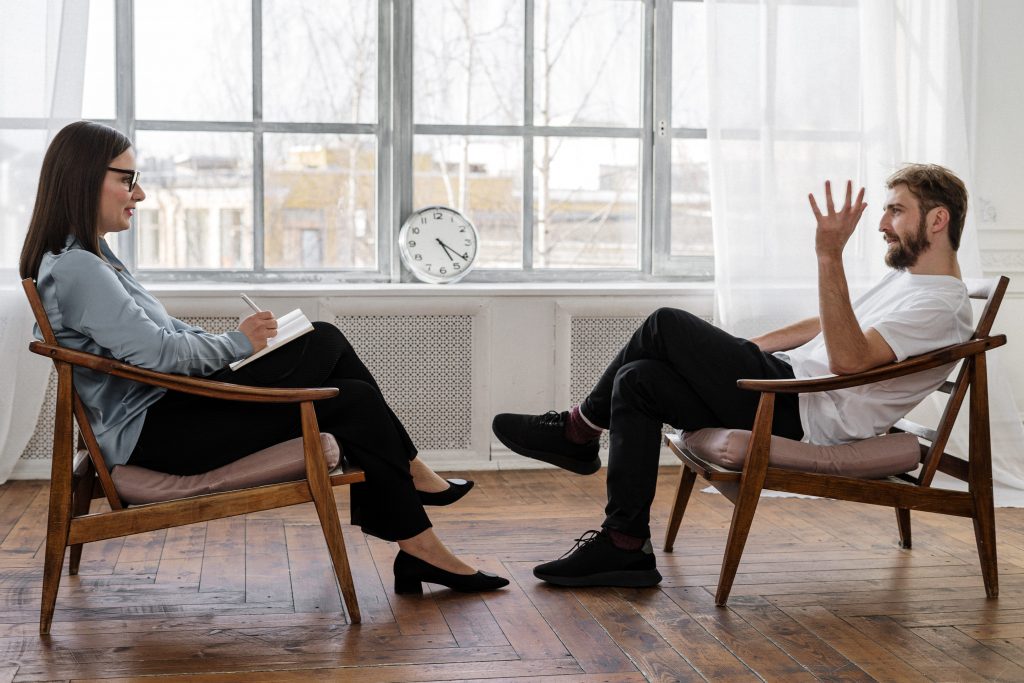 man and woman sitting on chairs, talking in counselling