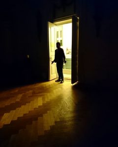man standing in a door, entering a dark room, light behind him