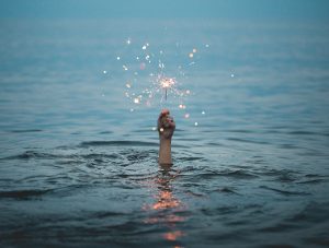 Someone holding a sparkler from below the water.