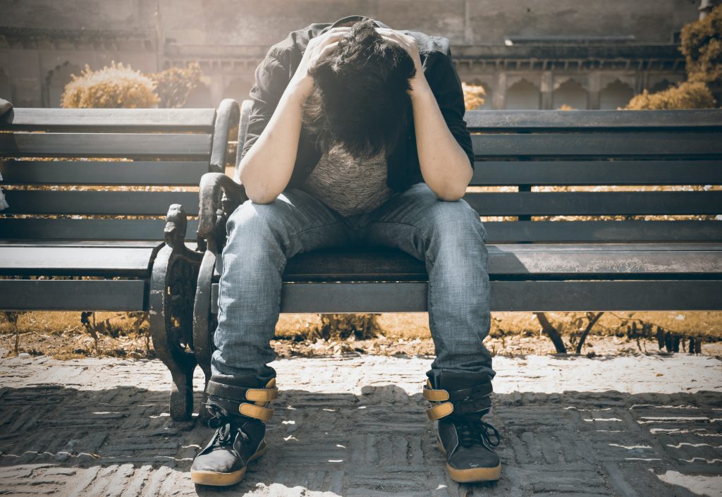 Man stressed on a park bench